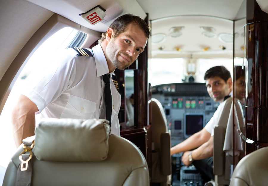 dos pilotos comerciales en cabina de avion mirando hacia la parte de atras del avion