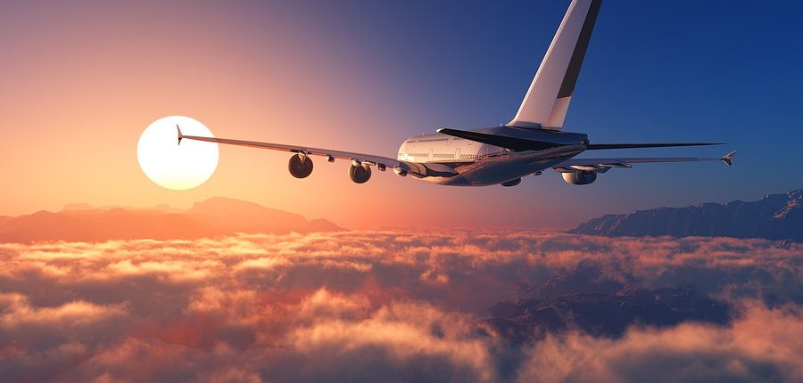 avion de pasajeros en vuelo hacia el sol con fondo de nubes y montanas