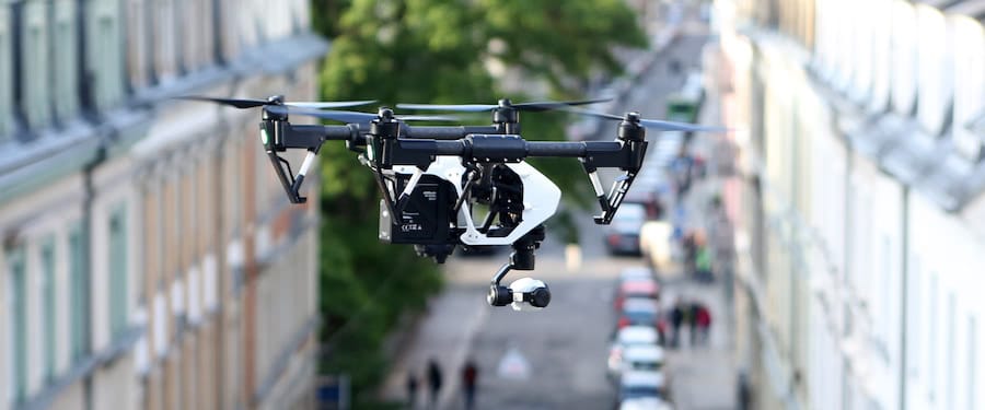 dron dji inspire en vuelo con fondo de edificios y coches difuminados