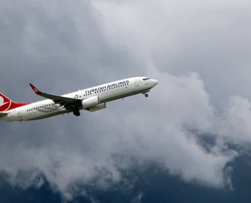 avion de la aerolinea turkish airlines sobrevolando una montaña rodeada de nubes