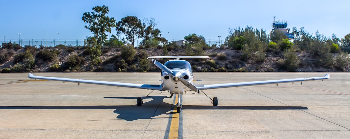 avioneta plateada en pista con fonde de vegetacion