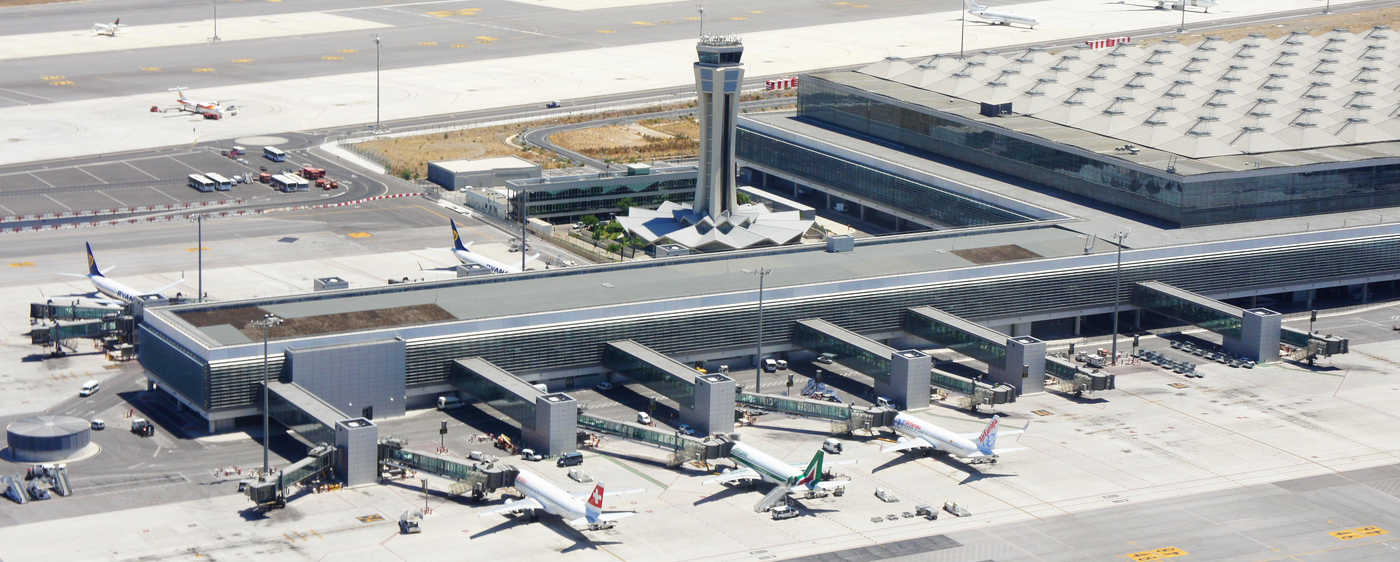 vista aerea de pista de aeropuerto con varios aviones cargando pasajeros y torre de control en el centro