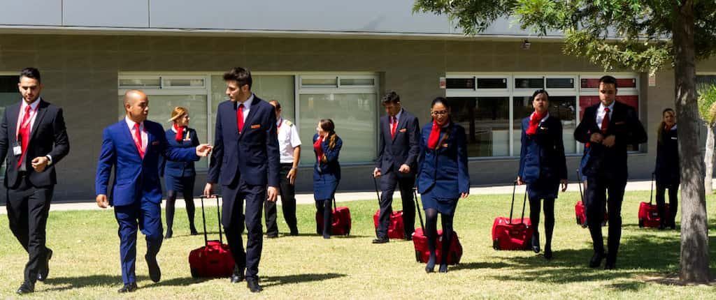 estudiantes del curso de tcp de air hostess malaga caminando sobre cesped uniformados y con maleta