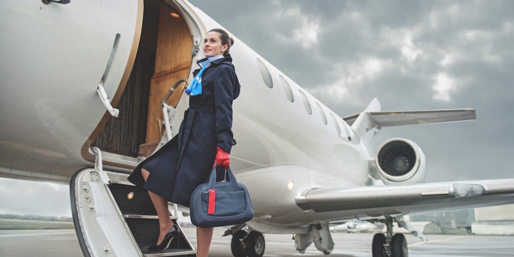 auxiliar de vuelo subiendo a avion con uniforme y maleta de mano