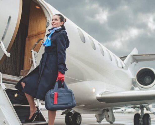 auxiliar de vuelo subiendo a avion con uniforme y maleta de mano