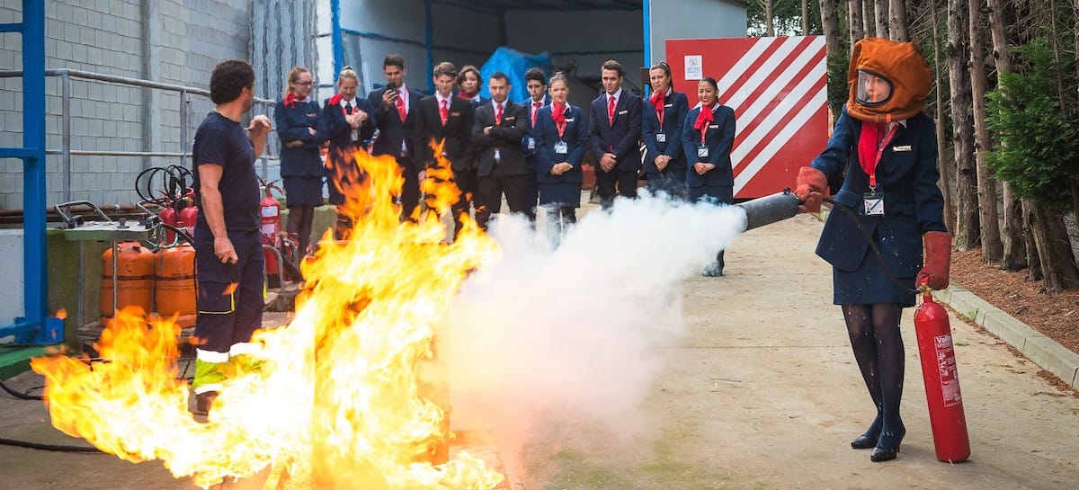 estudiante de tcp de air hostess apagando un fuego durante las practicas de emergencias